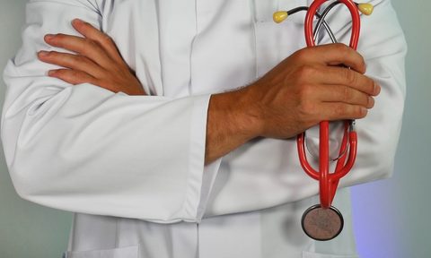arms of doctor with red stethoscope
