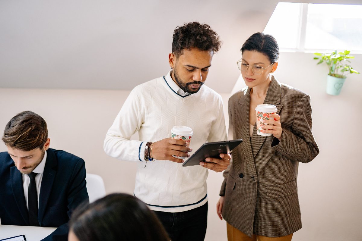 a man in a crewneck sweater speaking with a woman in a blazer