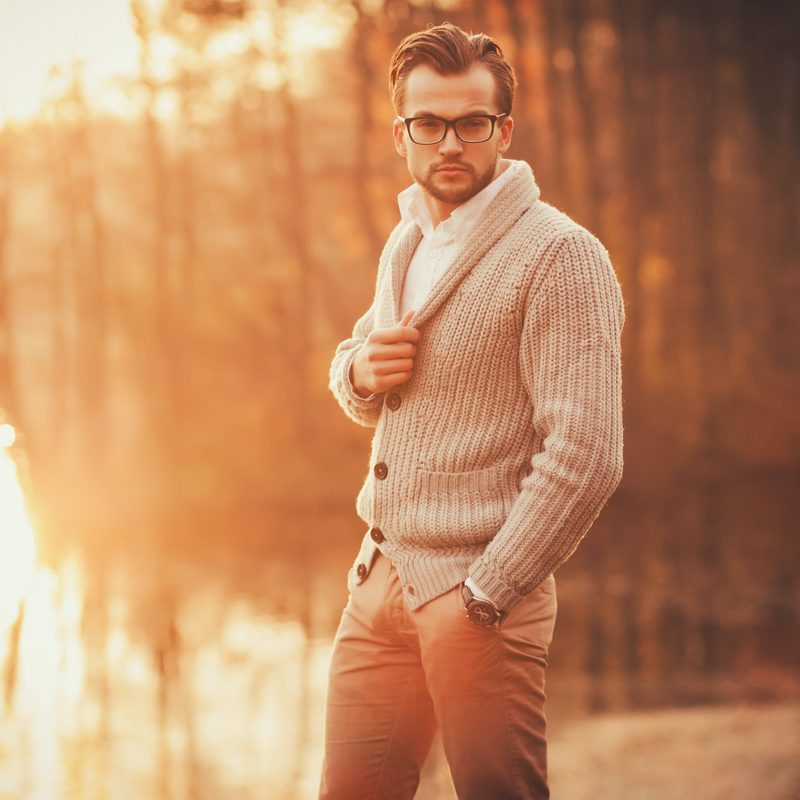 Trendy handsome man posing in autumn park alone