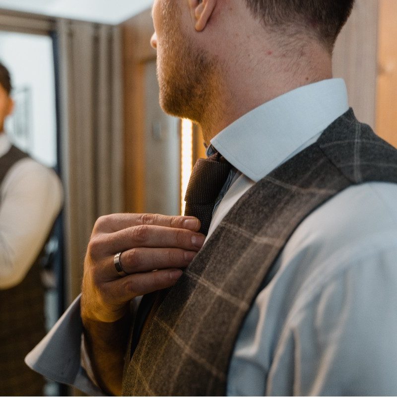 Man looking in the mirror with a vest and tie