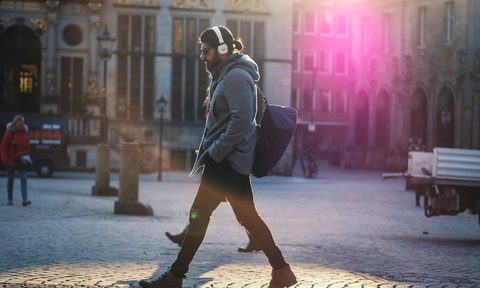 A man walking down the street listening to music.