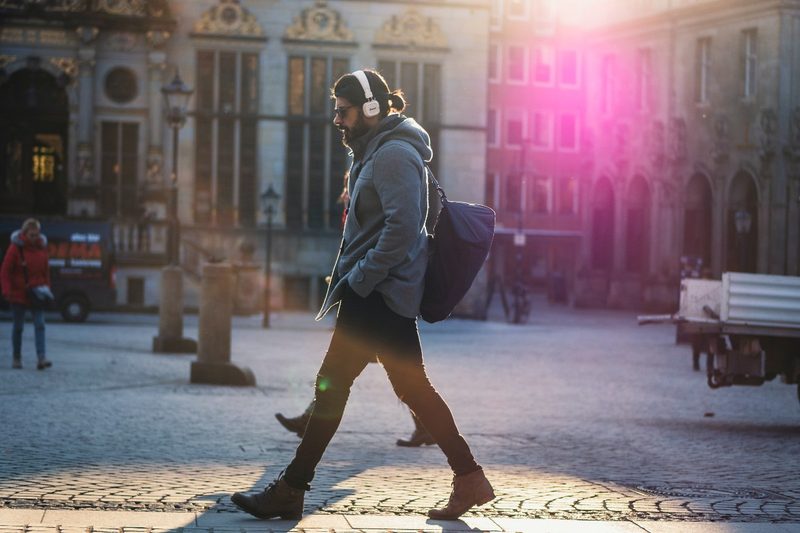 A man walking down the street listening to music.
