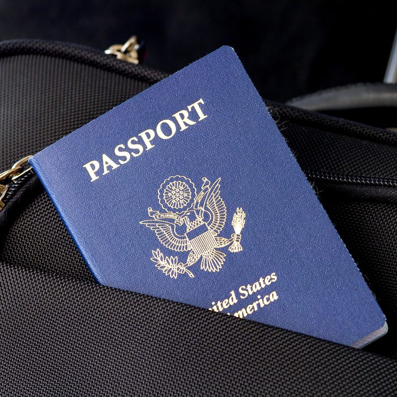 Passport sticking out of a suitcase pocket.