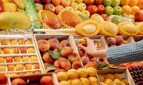 person choosing a peach from the produce section