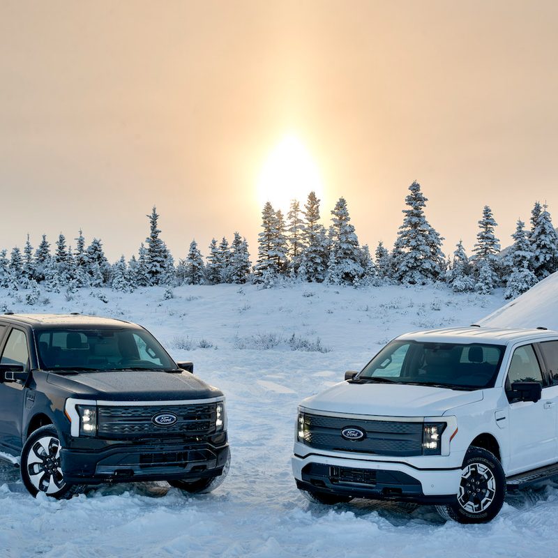 Two 2022 Ford F-150 Lightning testing in the snow in Alaska with snow on the ground.