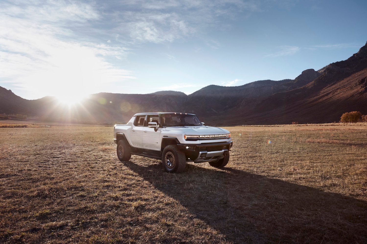 2022 GMC Hummer EV pickup truck in a desert with mountains in the back.