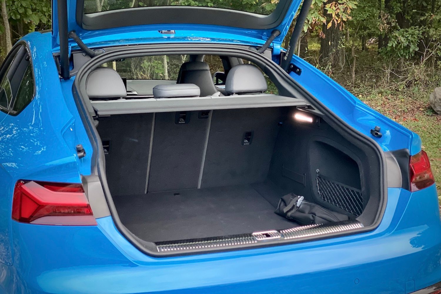 Close up of cargo space in the 2023 Audi S5 Sportback with trees in the back.