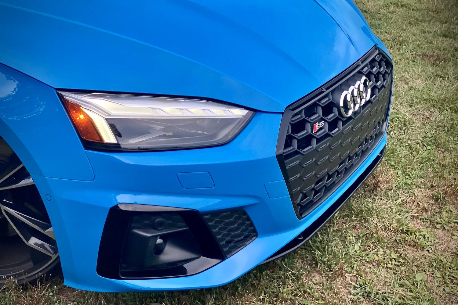 Close up of front end of 2023 Audi S5 Sportback in a grassy field.