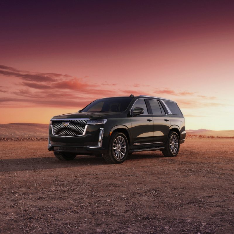 2023 Cadillac Escalade on a dirt mountain with the sun setting in the back.