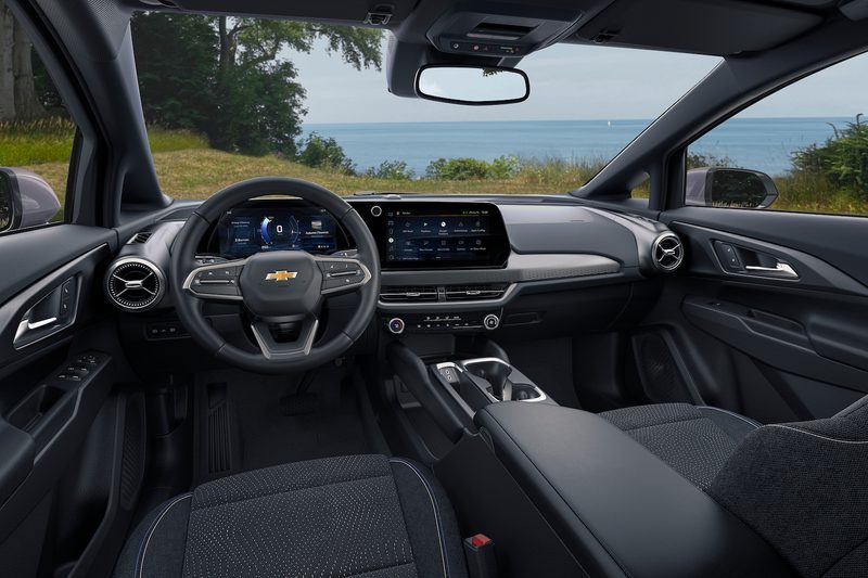 Close up of dashboard and steering wheel in the 2024 Chevrolet Equinox EV 1LT with water and trees in the back.