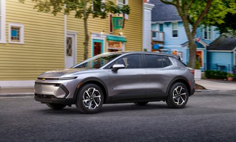 2024 Chevrolet Equinox EV 1LT from the driver's side angle driving down the street in front of a yellow building.