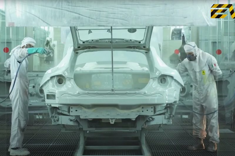 Ferrari workers at the automaker's factory painting a supercar on the factory line.