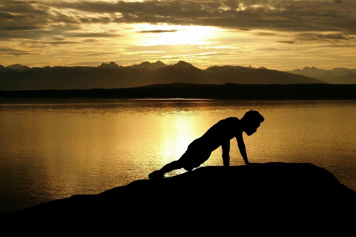 Health Crossfitter's silhouette. Lake, foothills, and sky in background.