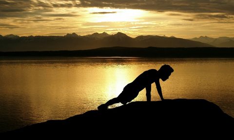 Health Crossfitter's silhouette. Lake, foothills, and sky in background.