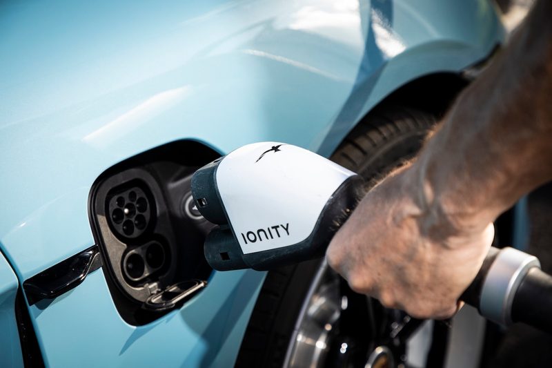 Man plugging a charger into a blue 2022 Porsche Taycan.
