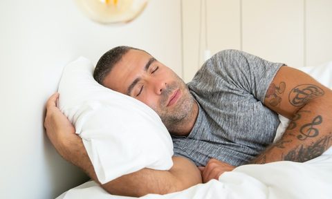A man sleeping on white bedding