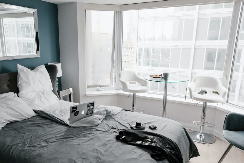 laptop on hotel bed with gray bedding