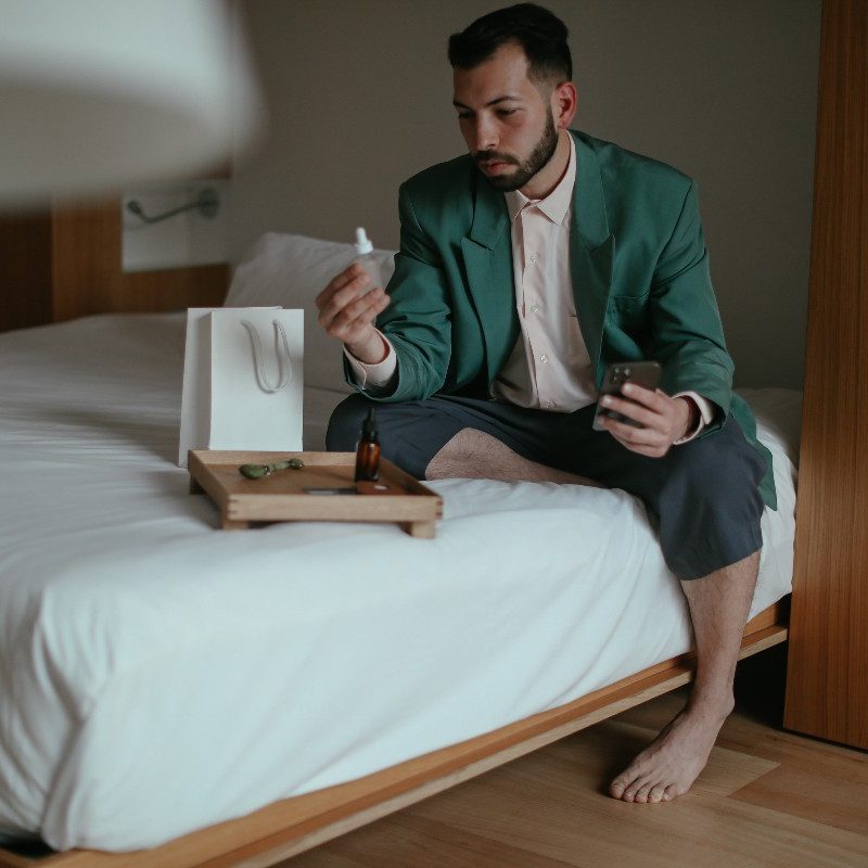 Man looking at skincare products in bed