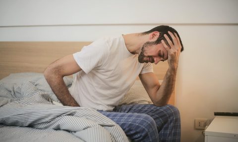 a man holding his back in bed