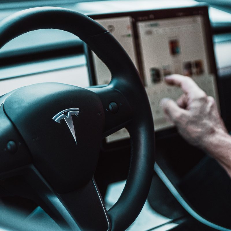 Person using the touchscreen feature while driving a Tesla