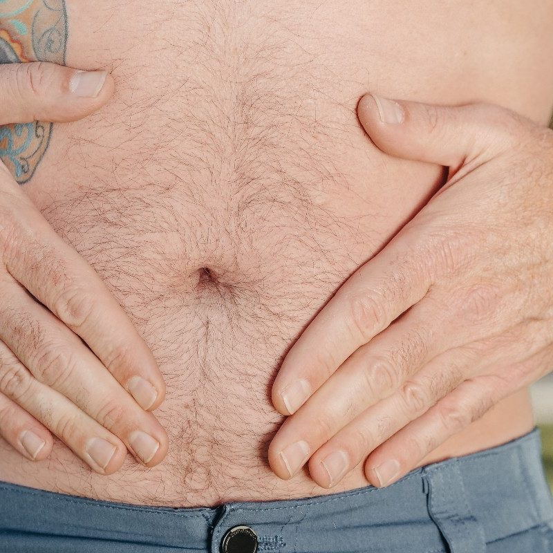 Man with tattoo bare stomach with hands in diamond shape around the belly button