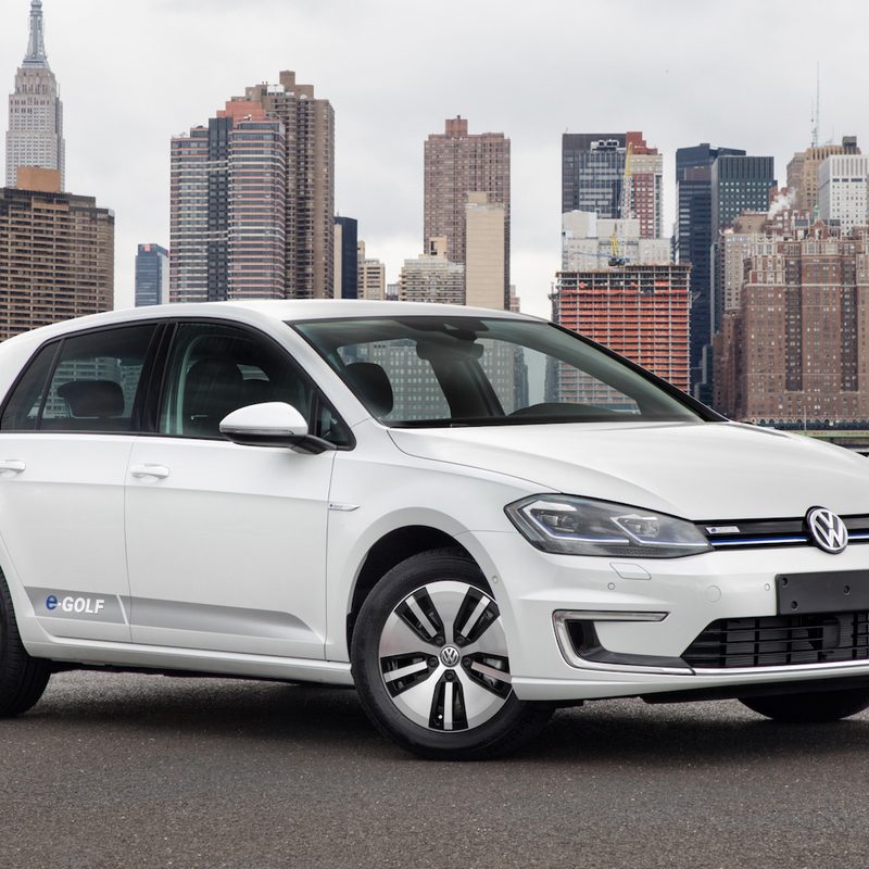 2017 Volkswagen e-Golf front end passenger's side angle parked in front of a city with tall buildings.