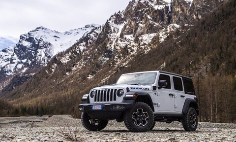 Front end angle of 2021 Jeep Wrangler Rubicon in front of snow-capped mountains on a rocky trail.