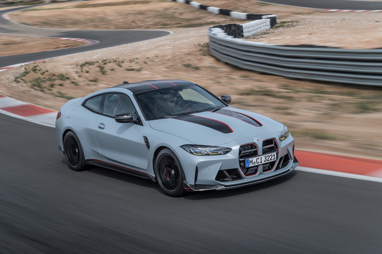 2022 BMW M4 CSL front end angle from passenger's drive driving on a racetrack with sand and dirt in the back.
