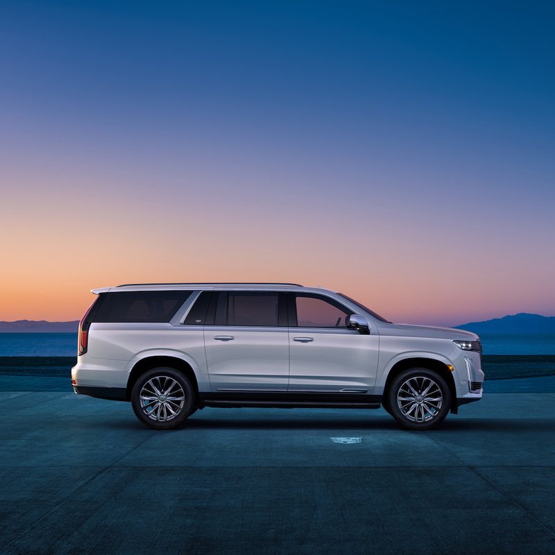 Side profile of 2023 Cadillac Escalade ESV in front of a mountain range at dawn.