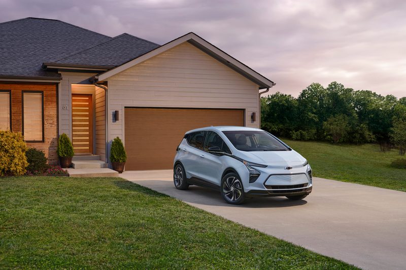 Front end angle of 2023 Chevrolet Bolt EV parked in front of a house during a sunset.