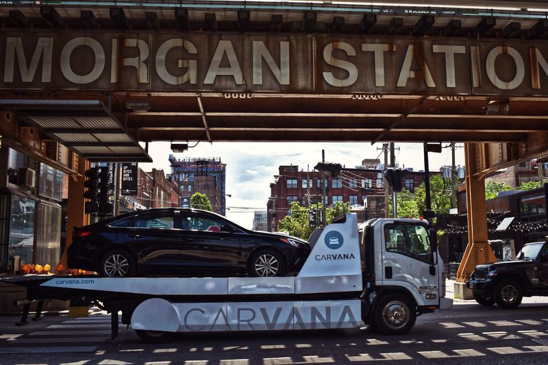 Black Hyundai Sonata sedan being towed on a Carvana truck in Chicago.