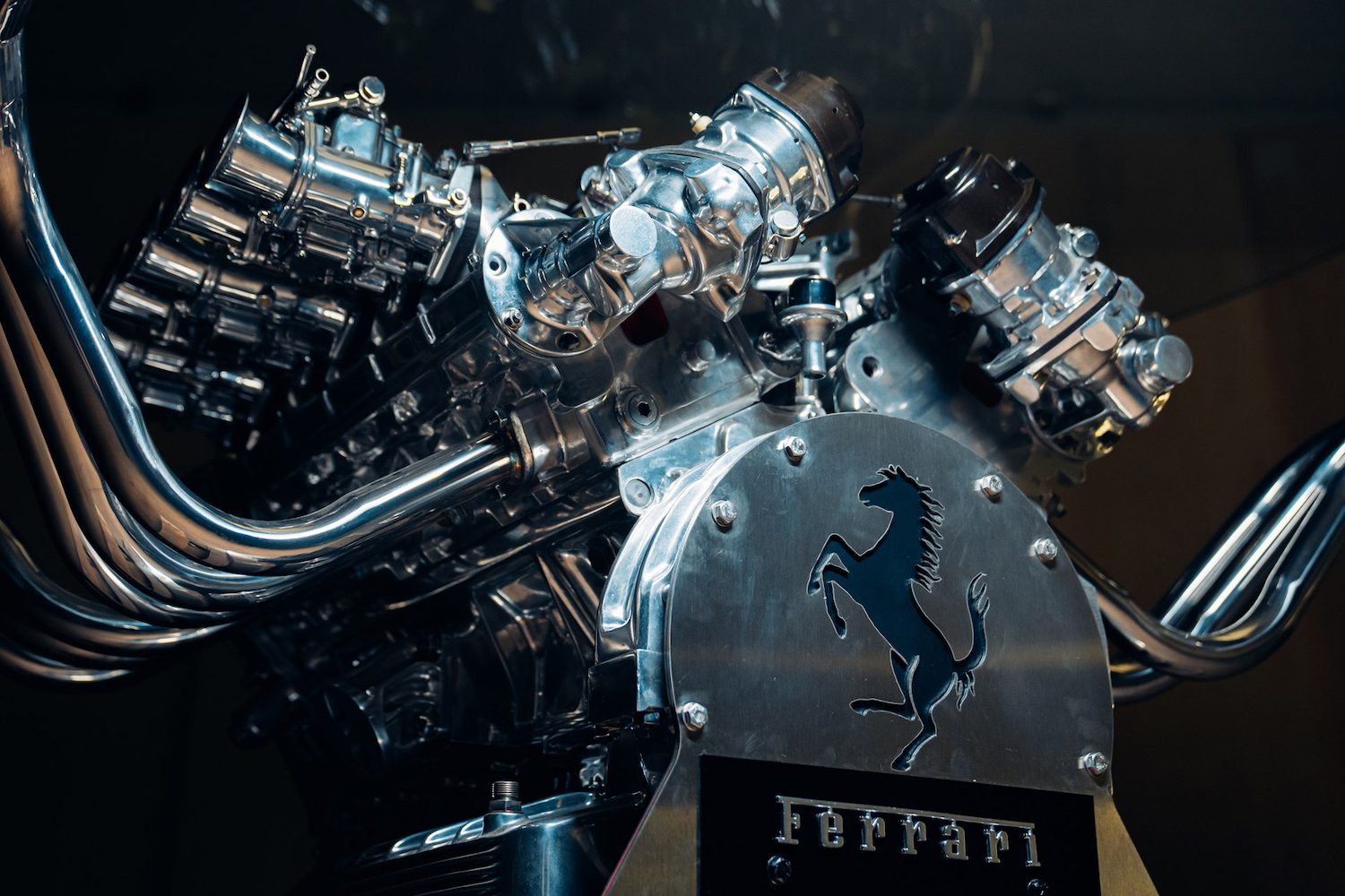 Lower end of Ferrari V12 Table with a close up of Ferrari badge in front of a black screen.