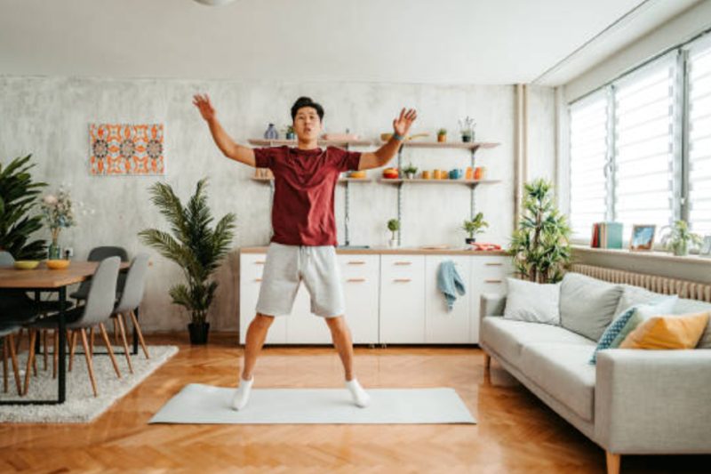 Man doing jumping jacks in living room.