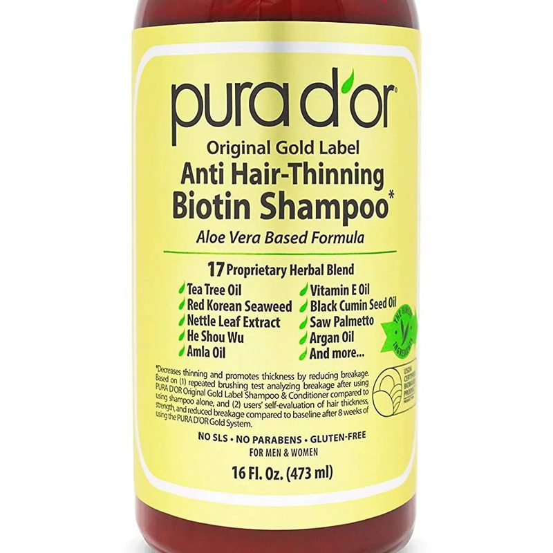 A close-up of a bottle of PURA D'OR Original Gold Label Anti-Thinning Biotin Shampoo.