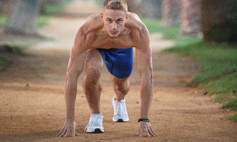 Shirtless man exercising on a trail outdoors.
