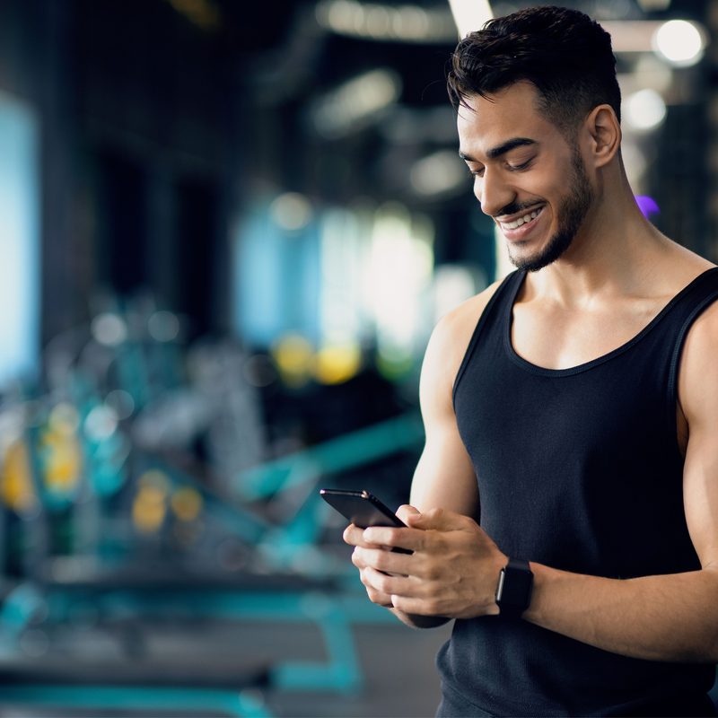 Man smiling down at his phone in the gym