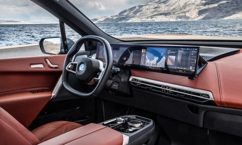 Close up of dashboard in 2022 BMW iX in front of a lake with snow-capped mountains in the back.