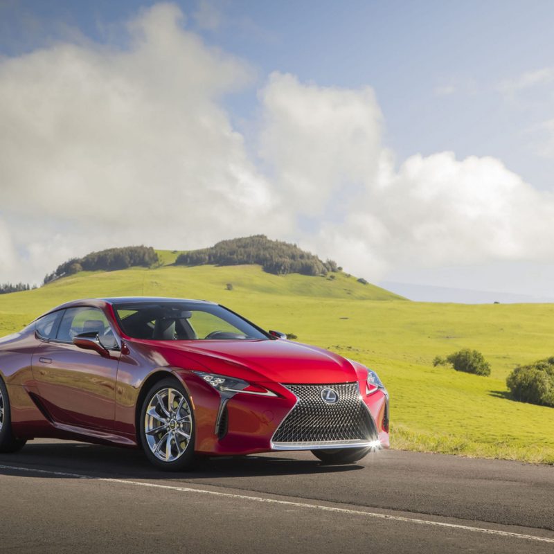 2022 Lexus LC front end angle parked on the side of the road in front of green grassy and hill.