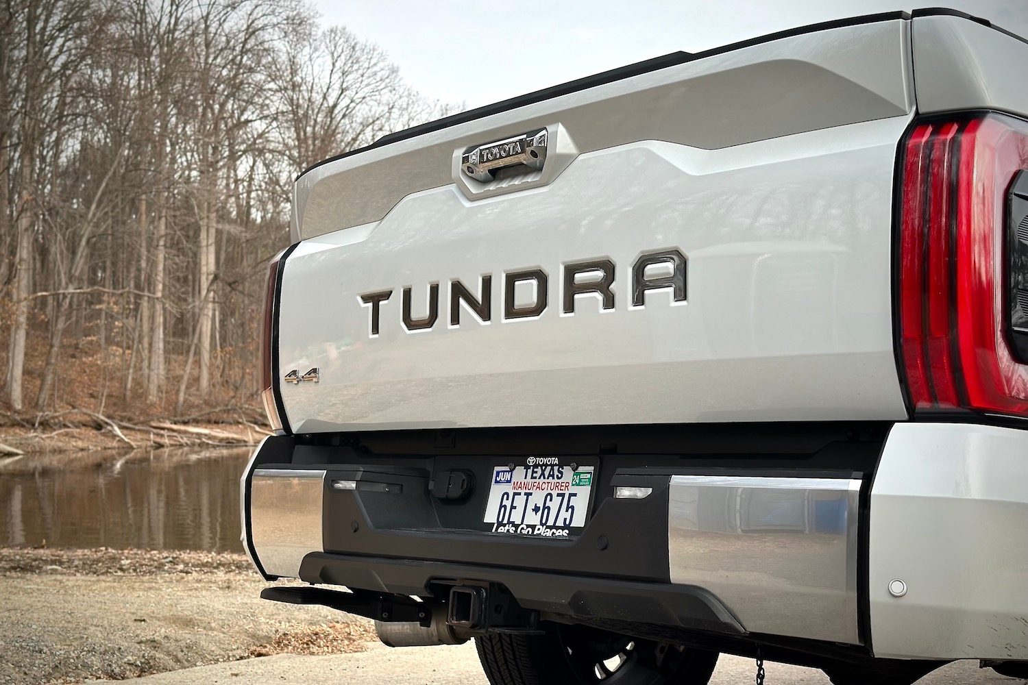 Close up of Tundra badged on the back of the 2022 Toyota Tundra Hybrid Capstone with trees in the background.