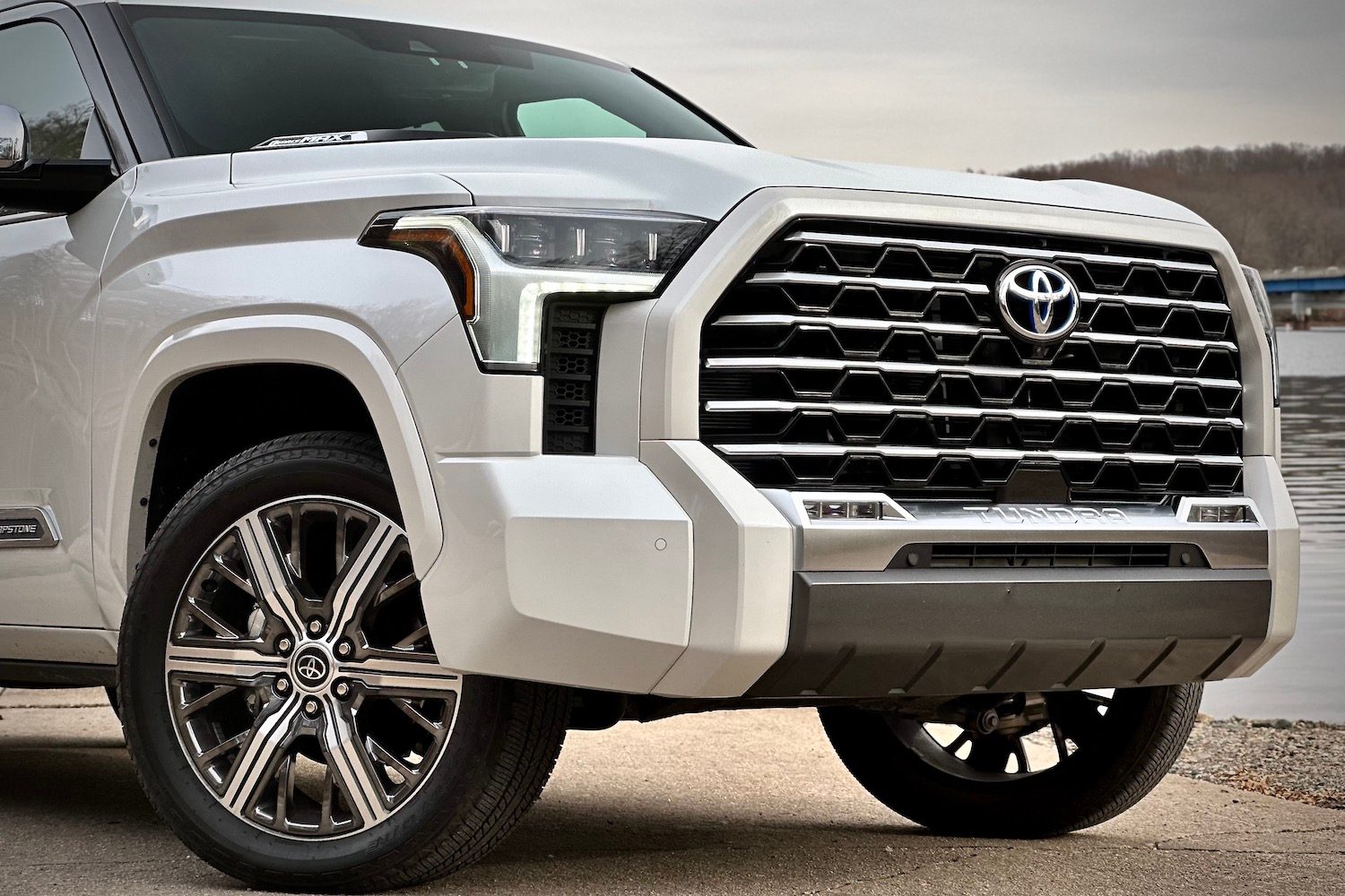 Close up of front end of 2022 Toyota Tundra Hybrid Capstone with water in the background.