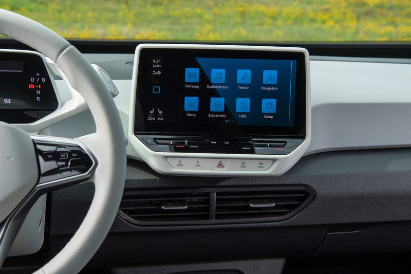 Close up of central touchscreen in the Volkswagen ID.3 with green grass in the back.