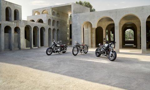 2023 BMW R 18 and R nineT 100 Years Editions in front of a villa during sunset and parked on a dirt parking lot.