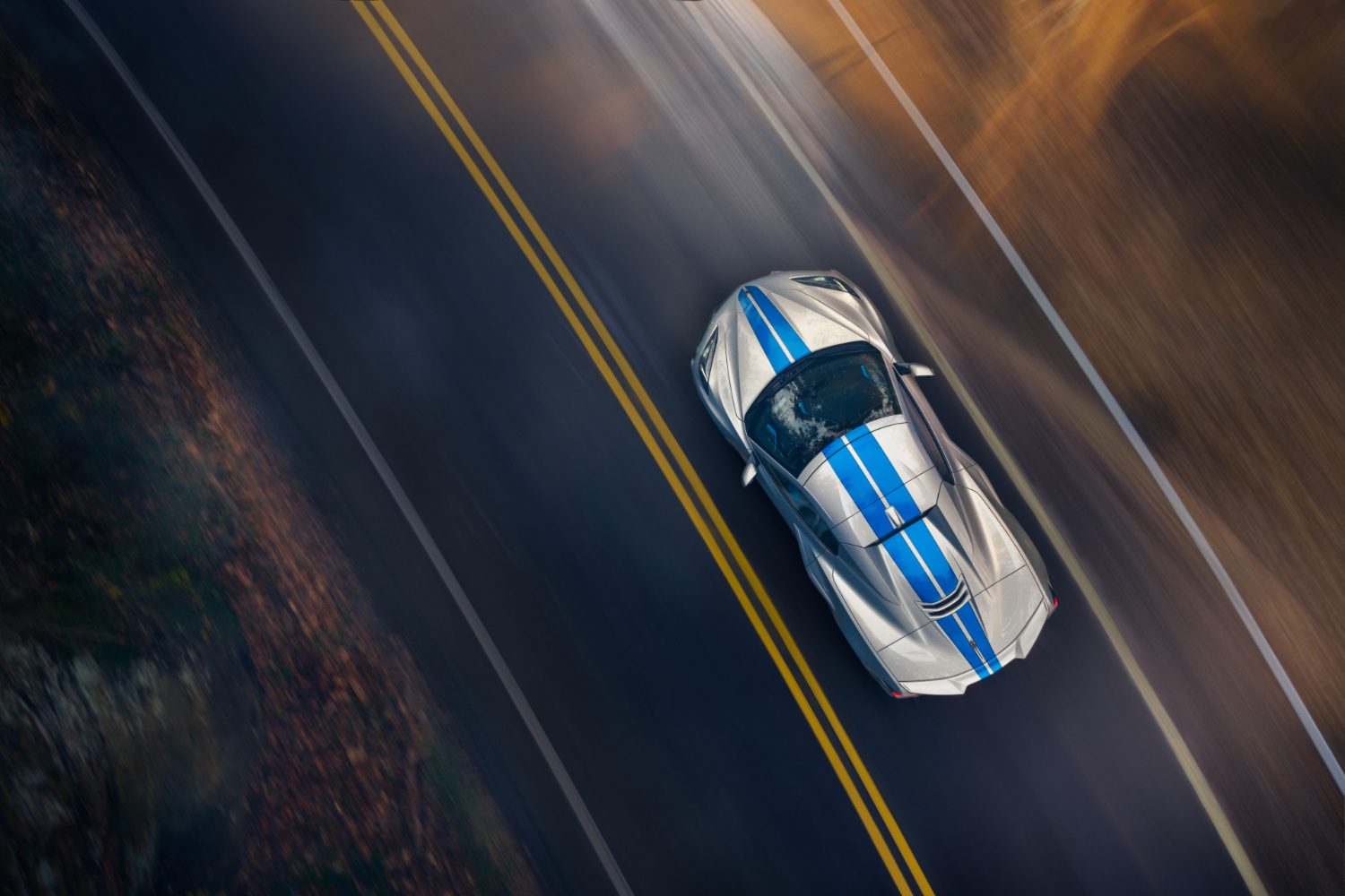 Overhead shot of 2024 Chevrolet Corvette E-Ray driving down the road with trees int he back.