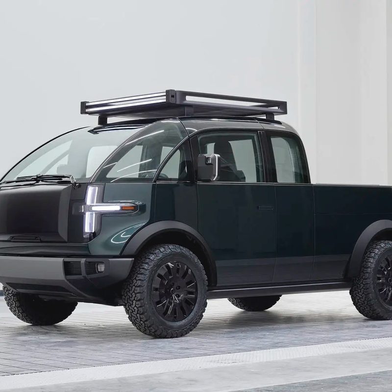 Canoo pickup truck front front end angle from driver's side in a studio with white walls in the back.
