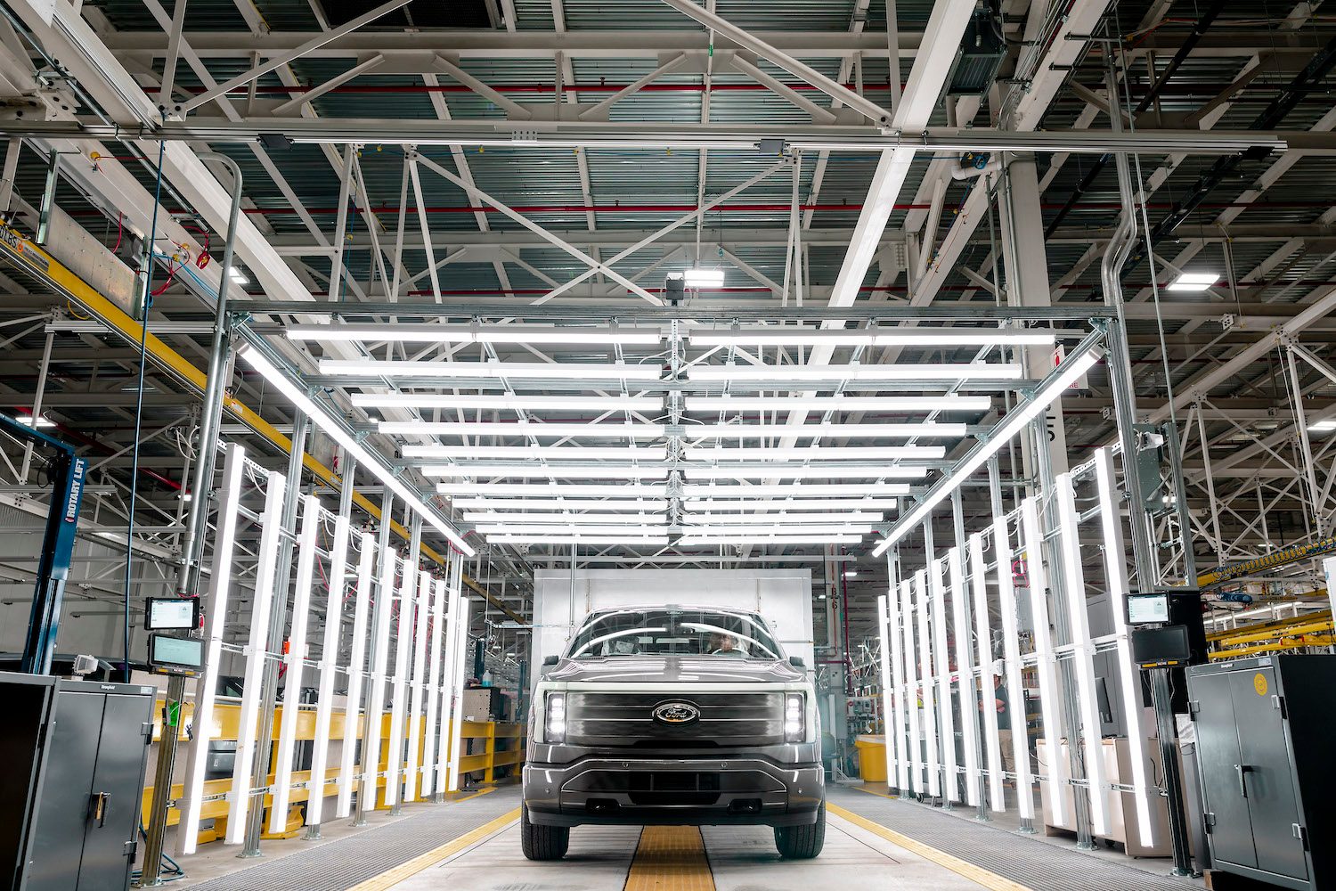 Ford F-150 Lightning at Ford's Rouge Electric Vehicle Center in a factory with bright lights in the back.