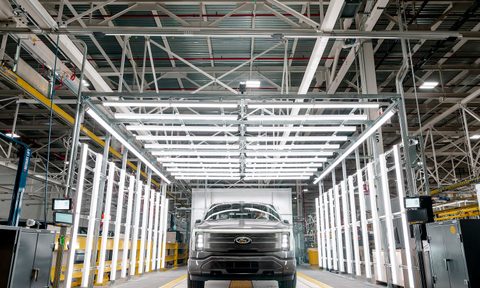 Ford F-150 Lightning at Ford's Rouge Electric Vehicle Center in a factory with bright lights in the back.
