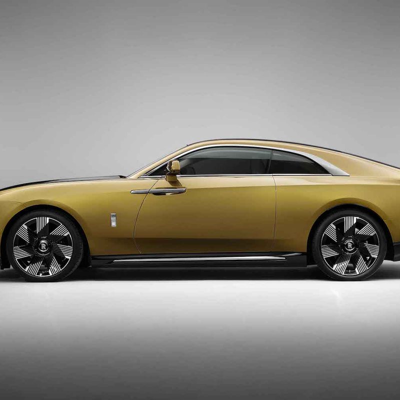 Rolls-Royce Spectre side profile in front of gray walls and studio lighting.