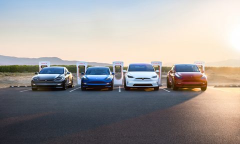Tesla group photo with Model S, Model 3, Model X, Model Y parked in front of charger during sunset.