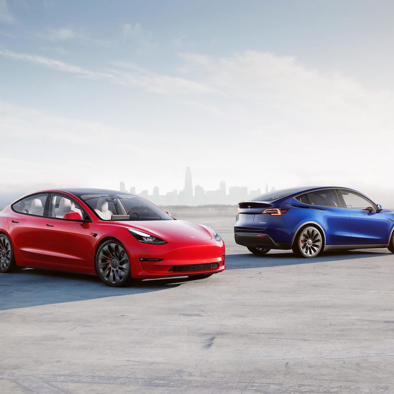 Tesla Model 3 and Model Y parked in front of a city skyline on a runway
