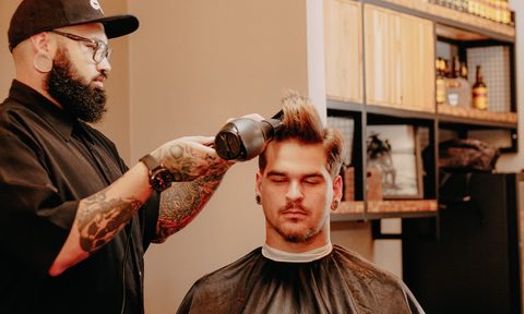 a man blow drying his hair at barber shop